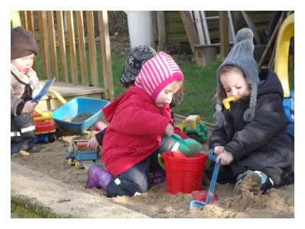 Die Tageskinder sitzen im großen Sandkasten des Spielegarten Lindental