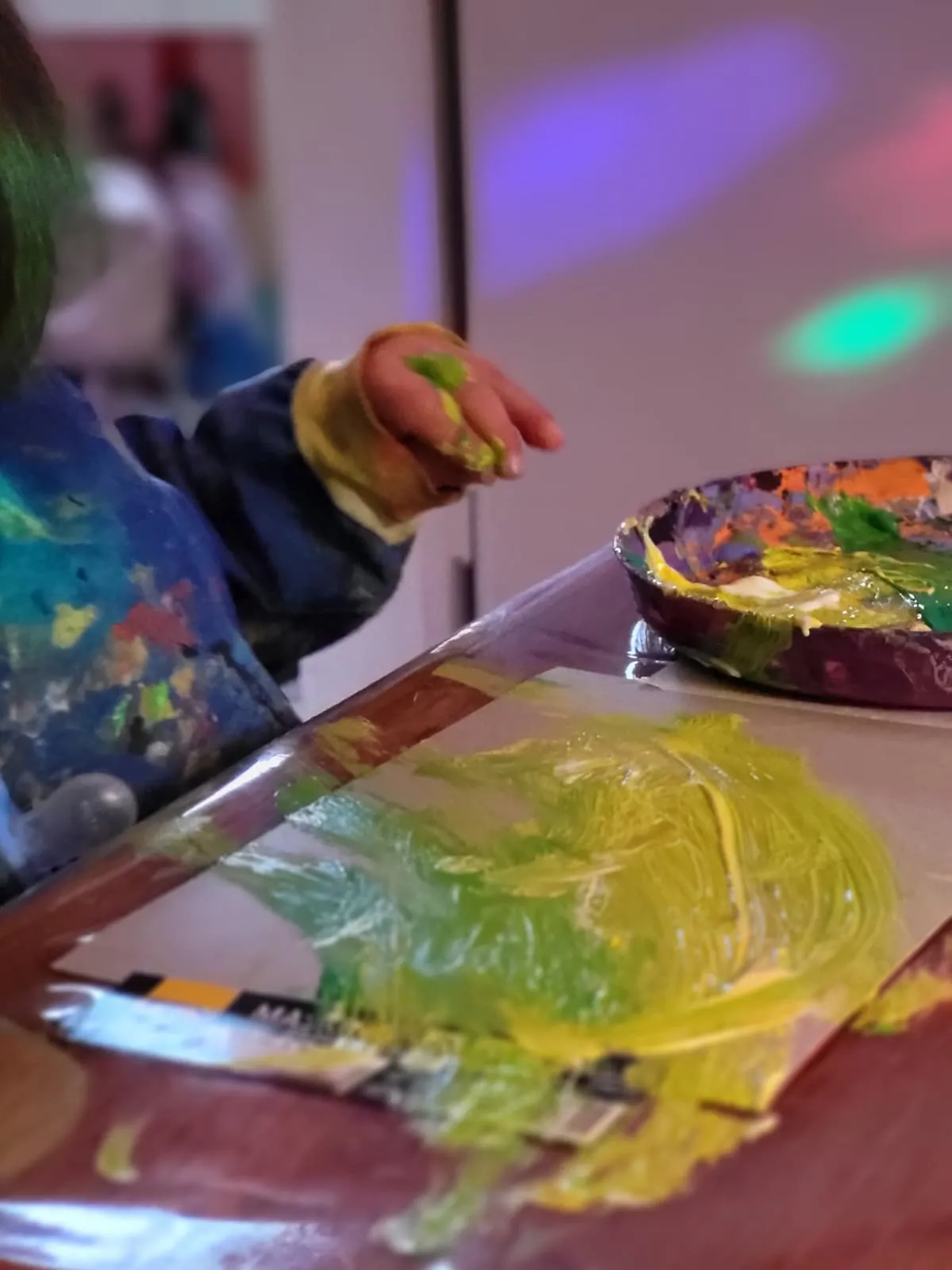 Kinderhand mit Fingerfarbe beim freien kreativen Gestalten